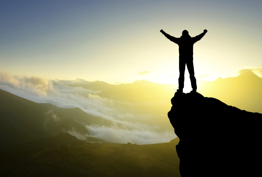 Man celebrating on a clifftop. Symbolizes overcoming the fear of asking for money